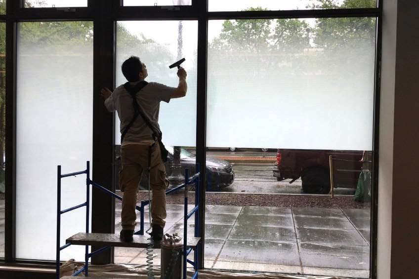 man installing gradient film on storefront